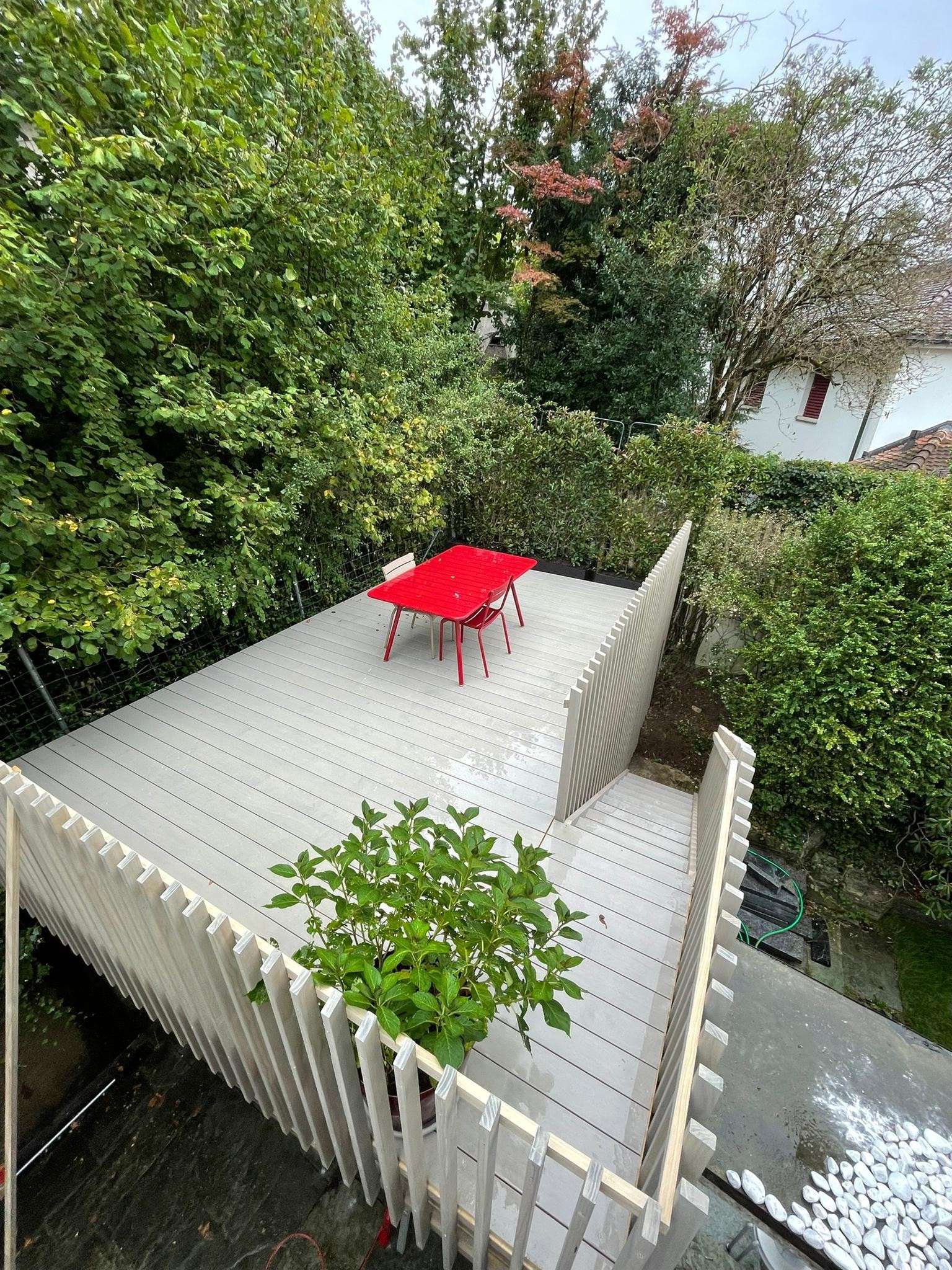 Terrasse aus Accoya Holz mit Vor-Vergrauungslasur, ergänzt durch eine integrierte Treppe, ein passendes Holzgeländer und eine Sitzbank; modernes, hochwertig verarbeitetes Aussenprojekt.