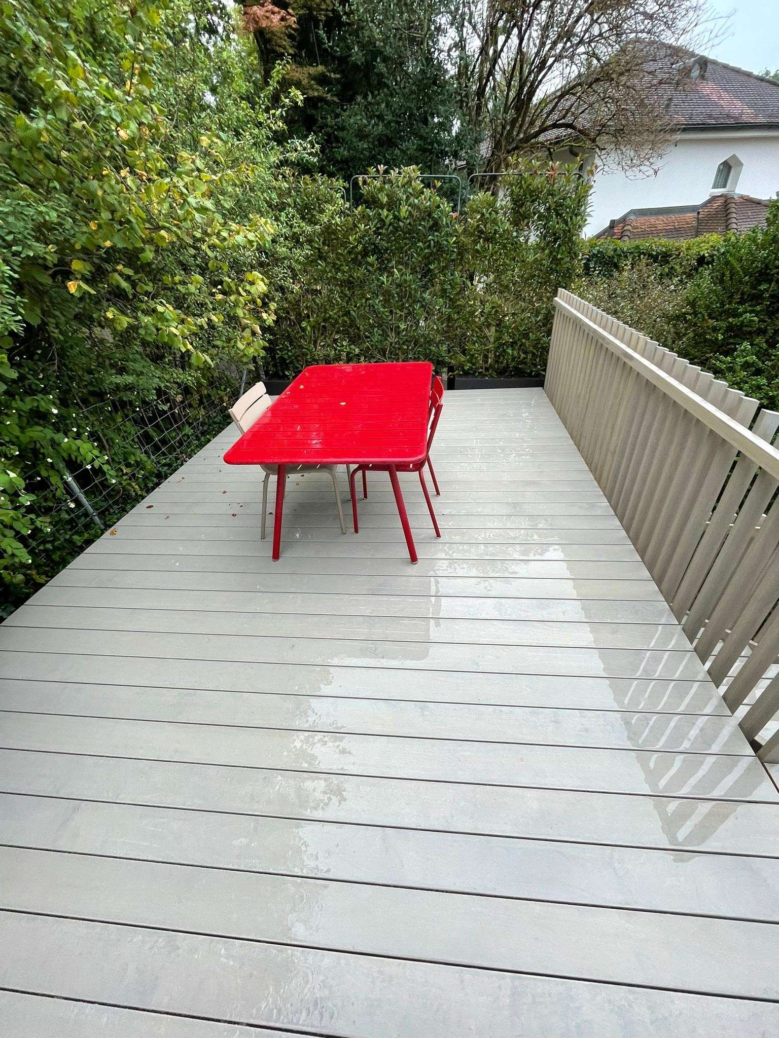 Terrasse aus Accoya Holz mit Vor-Vergrauungslasur, ergänzt durch eine integrierte Treppe, ein passendes Holzgeländer und eine Sitzbank; modernes, hochwertig verarbeitetes Aussenprojekt.