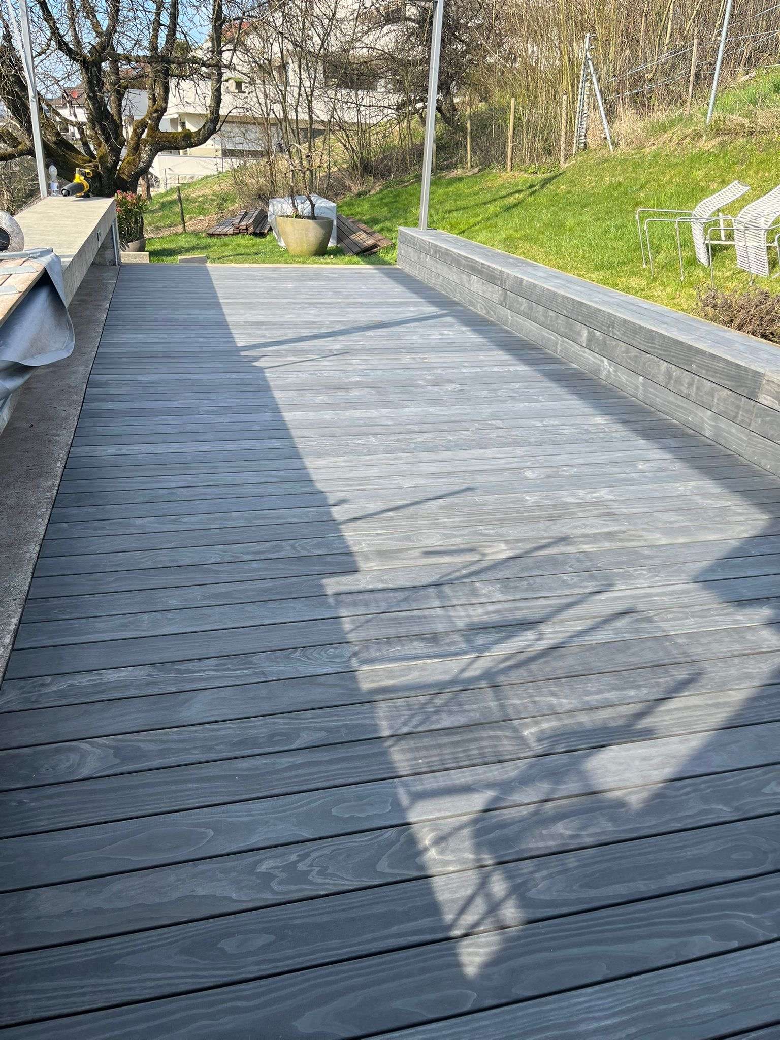 Accoya Grey Holzterrasse mit integrierter Sitzbank, unsichtbarer Clipbefestigung und langlebiger Aluminium-Unterkonstruktion.