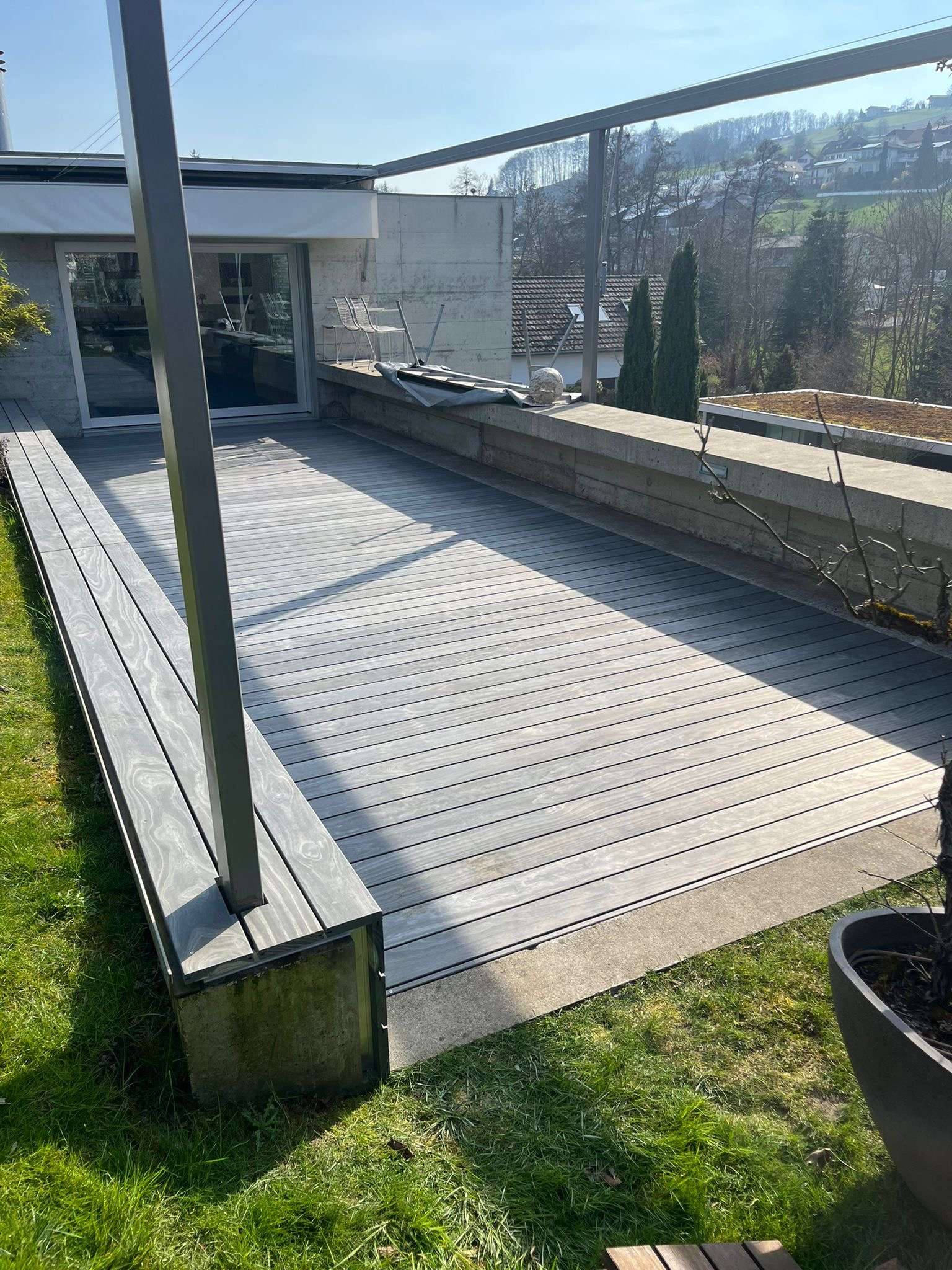 Accoya Grey Holzterrasse mit integrierter Sitzbank, unsichtbarer Clipbefestigung und langlebiger Aluminium-Unterkonstruktion.